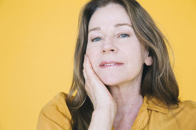 Portrait of senior woman against yellow background