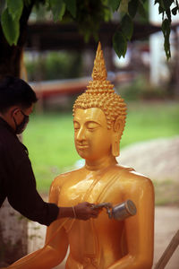 Close-up of man painting lord buddha statue