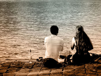 Rear view of people sitting by lake