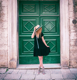 Full length of woman standing against door