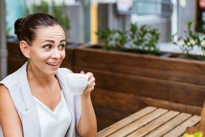 Positive business woman sitting in outdoor cafe drinking coffee.