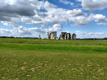 Stonehenge on green field against sky