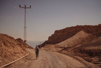 Man walking on road against clear sky