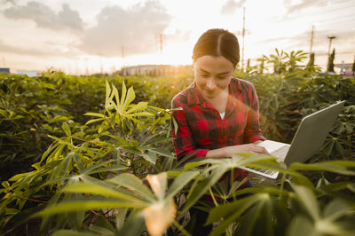 Young woman looking away while sitting on plants