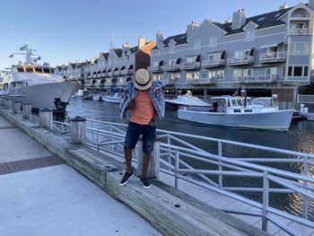 Rear view of man on railing against sky