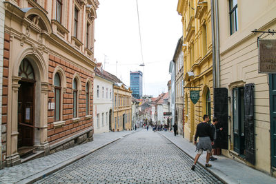 Rear view of woman walking on street amidst buildings in city