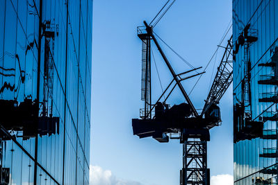 Low angle view of crane against blue sky