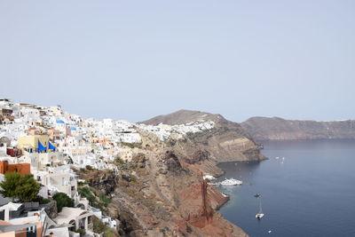 Buildings by sea against clear sky