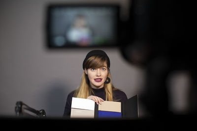 Female entrepreneur explaining about product while video recording on camera in creative office