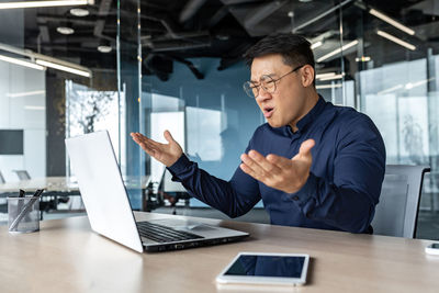 Side view of man using laptop at office