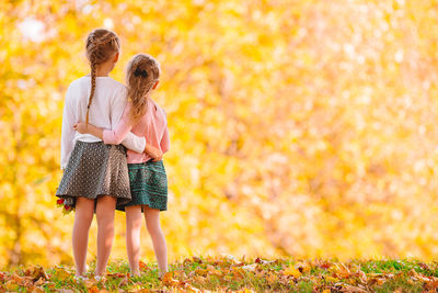 Rear view of girls looking at trees in autumn