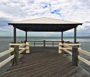 Pier on sea against cloudy sky