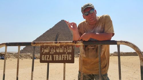 Man leaning on fence against giza pyramids