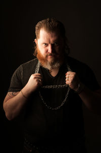 Portrait of man holding camera over black background