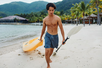 Rear view of shirtless man standing at beach