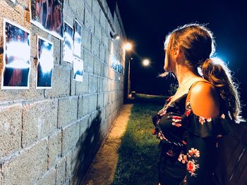 Rear view of woman standing at illuminated night