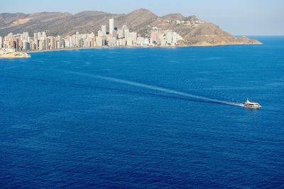 Boat in sea with city and hills in background