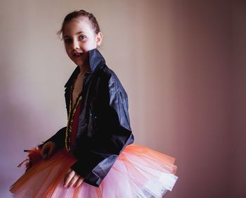 Side view of confident girl wearing tutu and jacket against wall