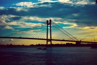 Suspension bridge over river against sky during sunset