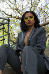 Businesswoman wearing sunglasses looking away while sitting on steps outdoors