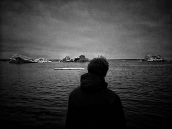 Rear view of man in front of sea against sky