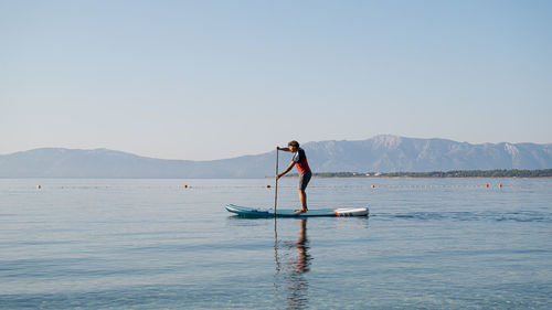 Man standing in sea against clear sky