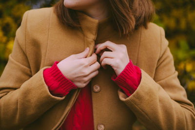 Midsection of woman with buttoning sitting on field