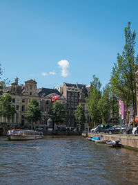 Buildings by river against sky in city