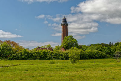 Lighthouse and trees on field against sky