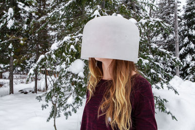 Woman wearing hat against trees during winter