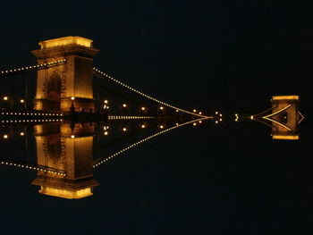 Illuminated suspension bridge over river at night