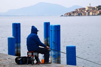 Side view of man fishing on pier over lake