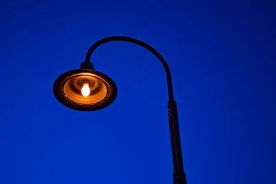 Low angle view of illuminated lamp against blue sky