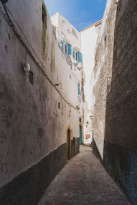 Walkway amidst buildings against sky