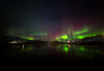 Reflection of aurora polaris on lake against sky