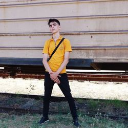 Young man looking away while standing against wall