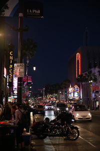 Vehicles on road by illuminated buildings in city at night