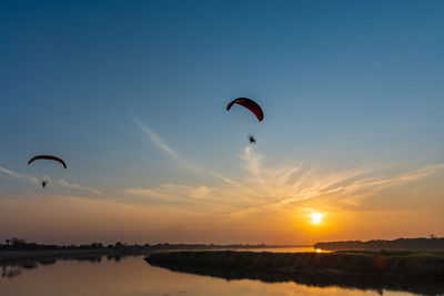 People paragliding against sky during sunset