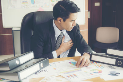 Businessman with heart pain sitting at desk sitting in office