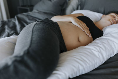 Pregnant woman sleeping on pregnancy pillow on bed