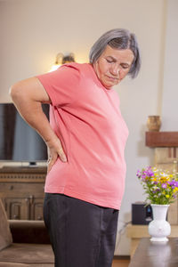 Woman with backache standing at home