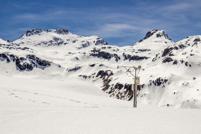 Pole on snowcapped mountain against sky