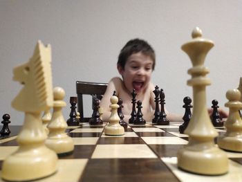 Boy screaming while playing chess on table