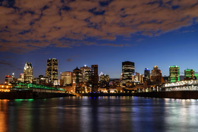 Colorful light reflecting on river against cityscape