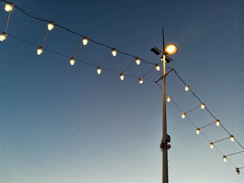 Low angle view of illuminated street lights against clear sky