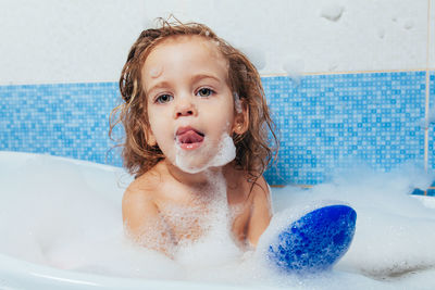 Cute shirtless girl sitting in bathtub at home