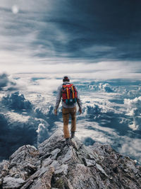 Rear view of man standing on rock against sky