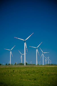 Wind turbines on field against clear sky