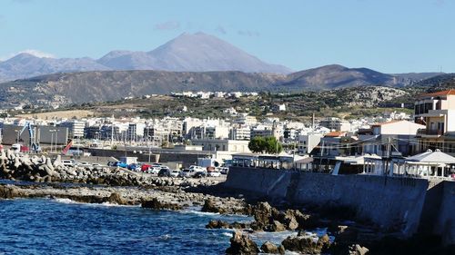 Town by sea and mountains against sky