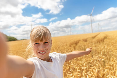 Portrait of young woman standing on field against sky